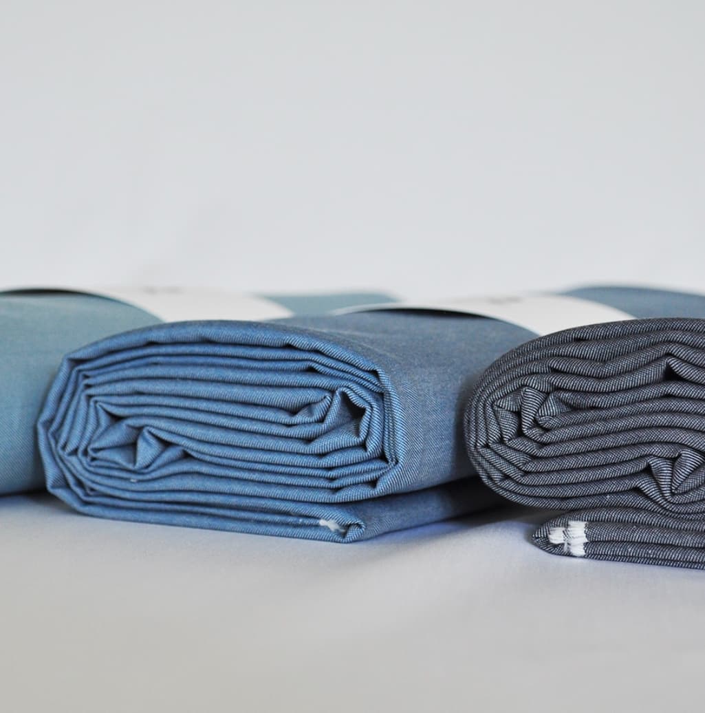 Folded blue shirting fabric rolls from Ortega Textile
